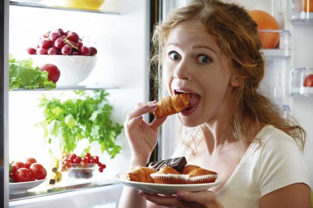 женщина ест у холодильника